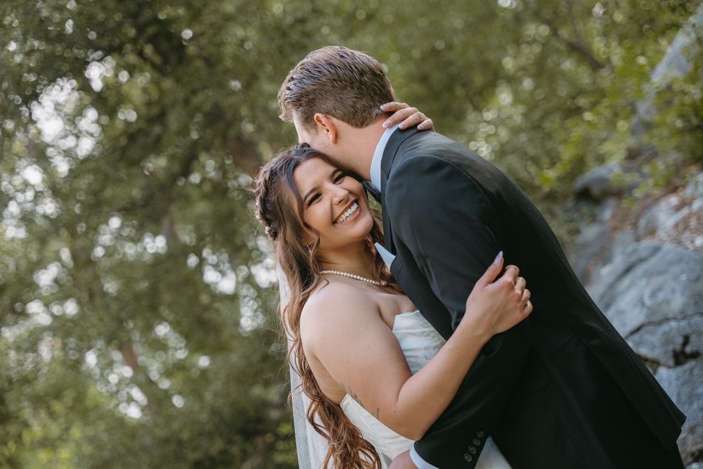 Two people embracing and laughing together outdoors in a candid romantic moment.