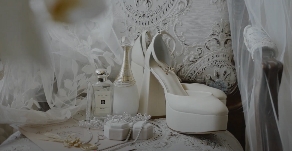 White platform wedding heels and tulle veil arranged with delicate lace and accessories for bridal preparation.