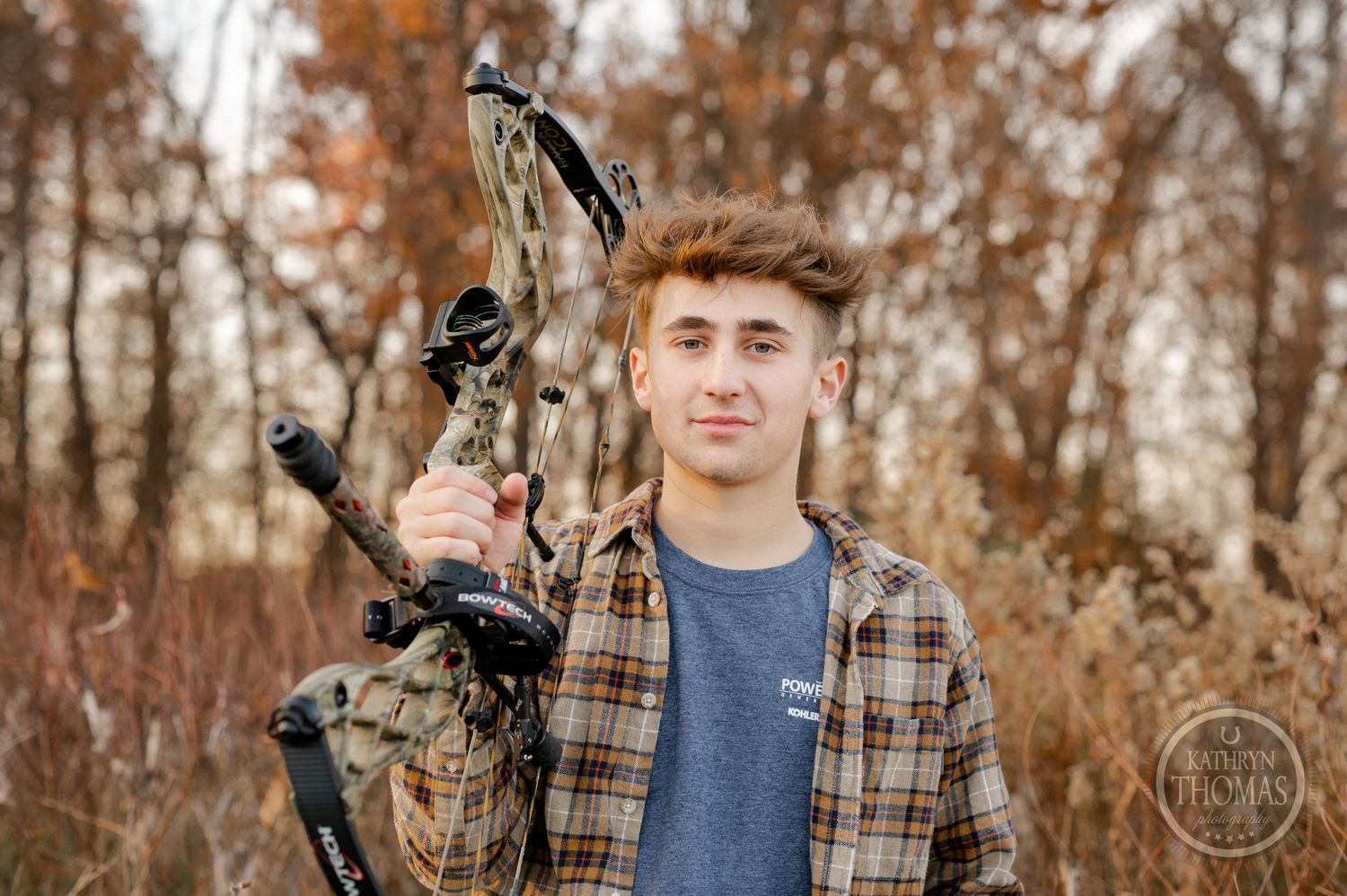 Close-up portrait of archer holding camouflage compound bow against autumn trees.