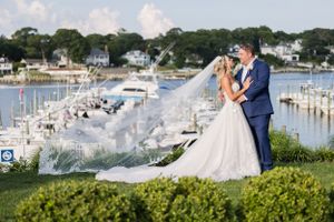 Coastal wedding photography with marina and boats in background on sunny day.