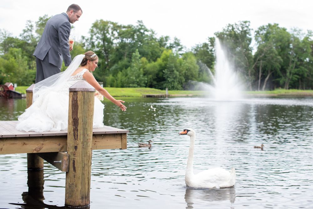 Wedding couple by lakeside fountain with scenic water views.