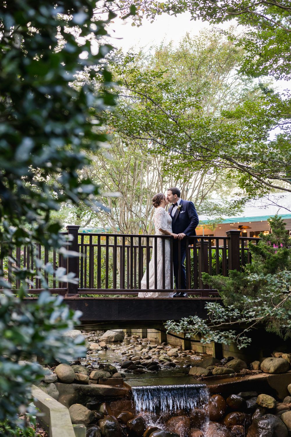 Romantic moment captured on rustic wooden bridge over stream with waterfall.