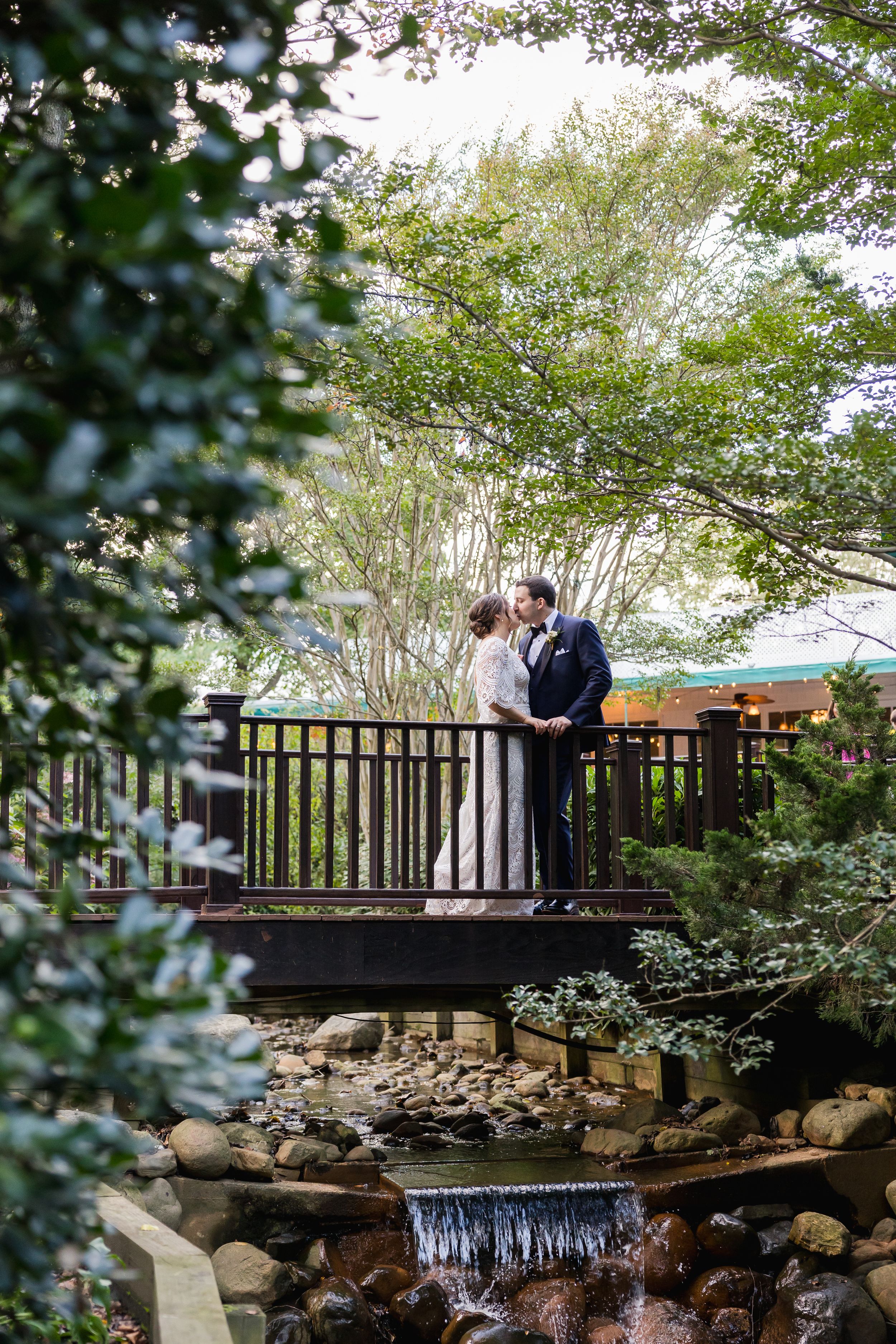 Romantic moment captured on rustic wooden bridge over stream with waterfall.