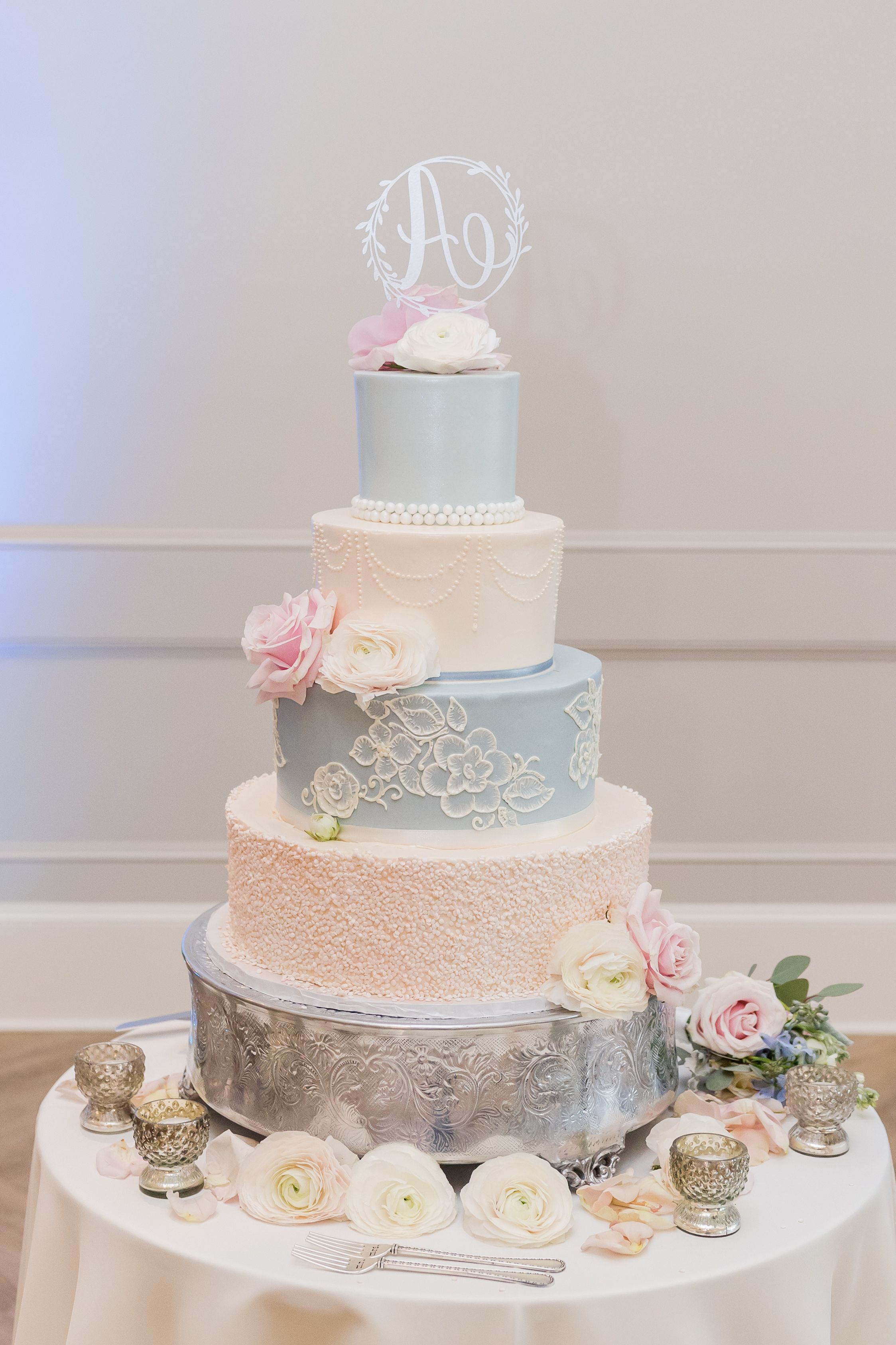 Elegant three-tiered wedding cake with blush roses and delicate lace details.