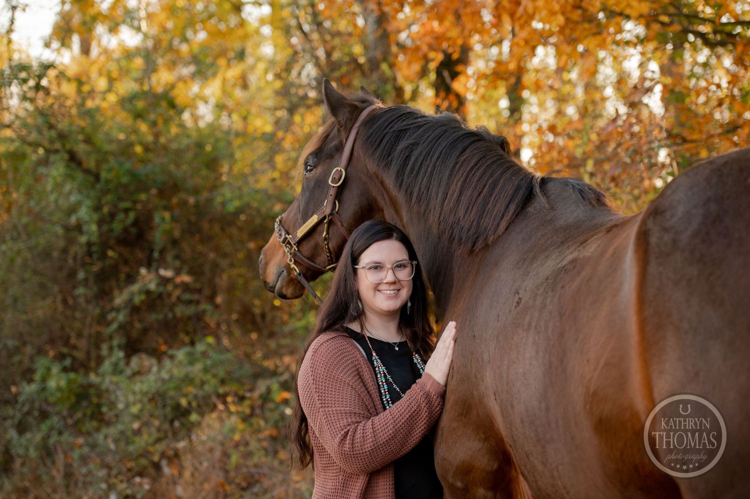 A beautiful bay horse and their companion share a tender moment during a fall photo session.