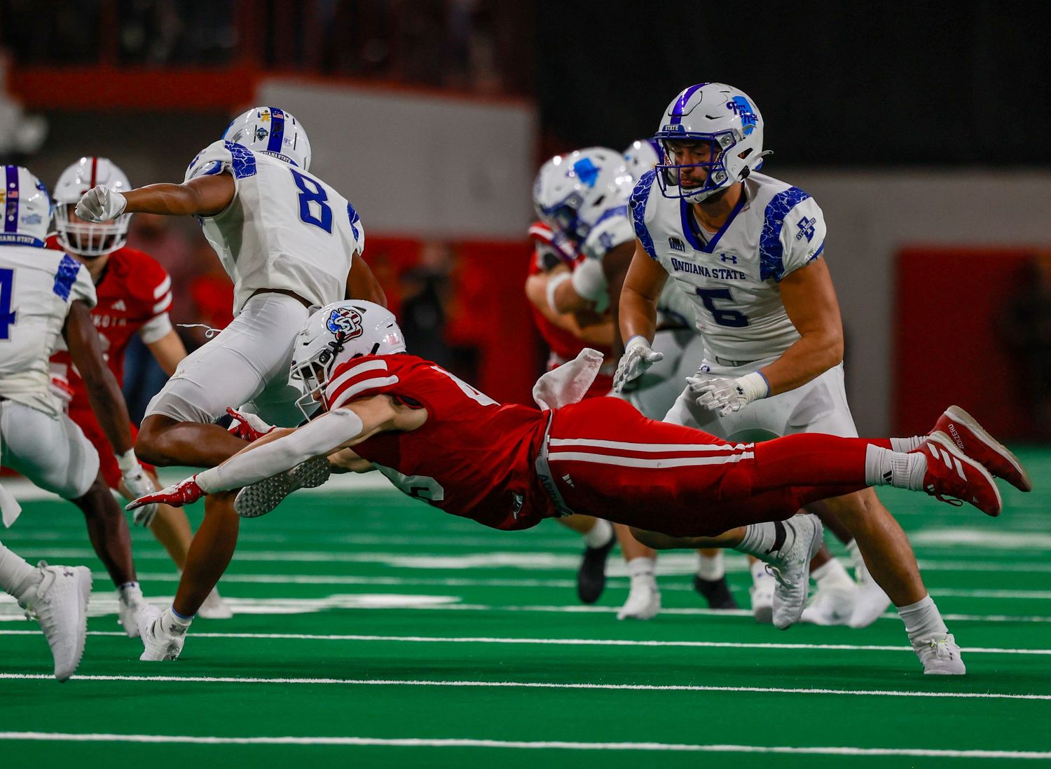 Defender leaping to catch the running back and is horizontal in the air
