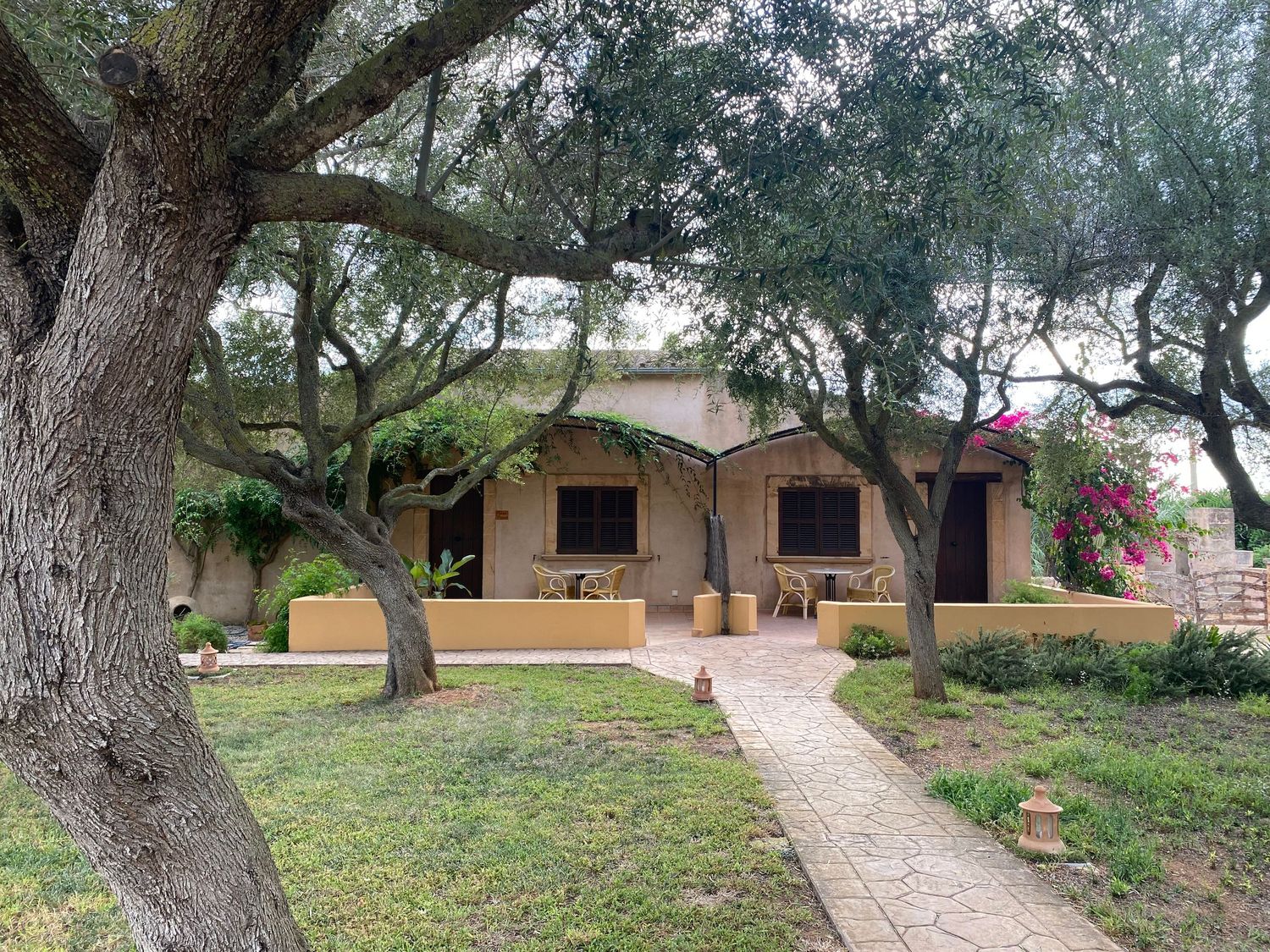 Spanish-style villa with terracotta roof and arched windows surrounded by lush trees and landscaping.
