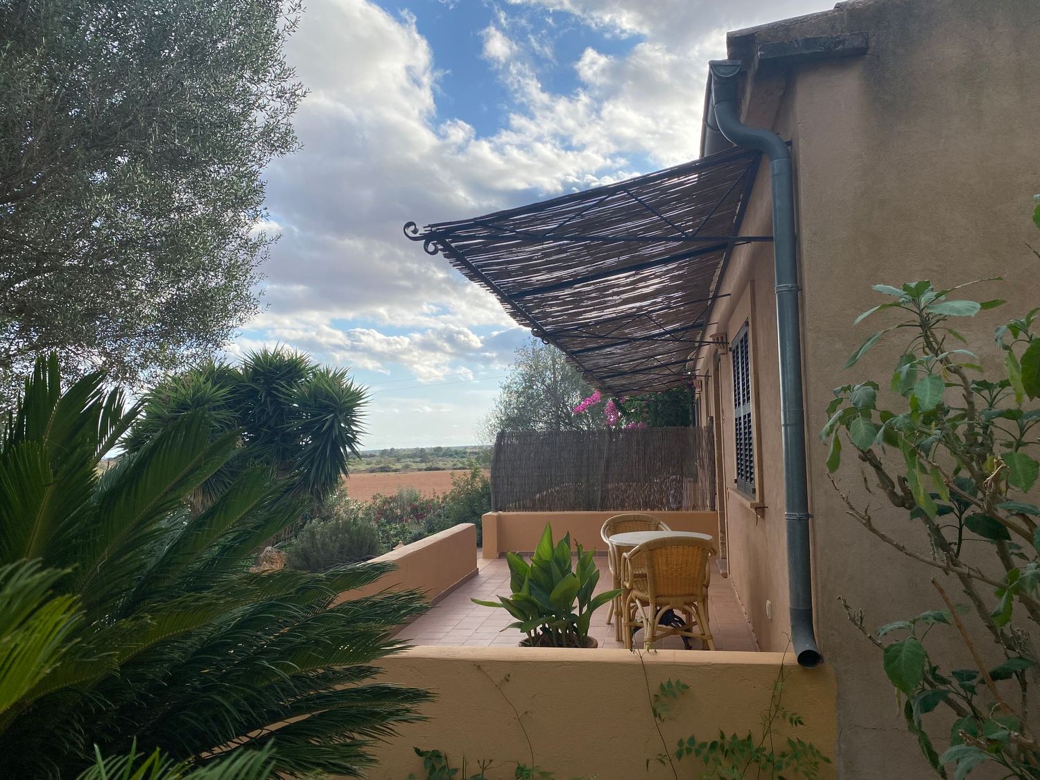 Private terrace with rustic wooden awning overlooking rural Mediterranean landscape.