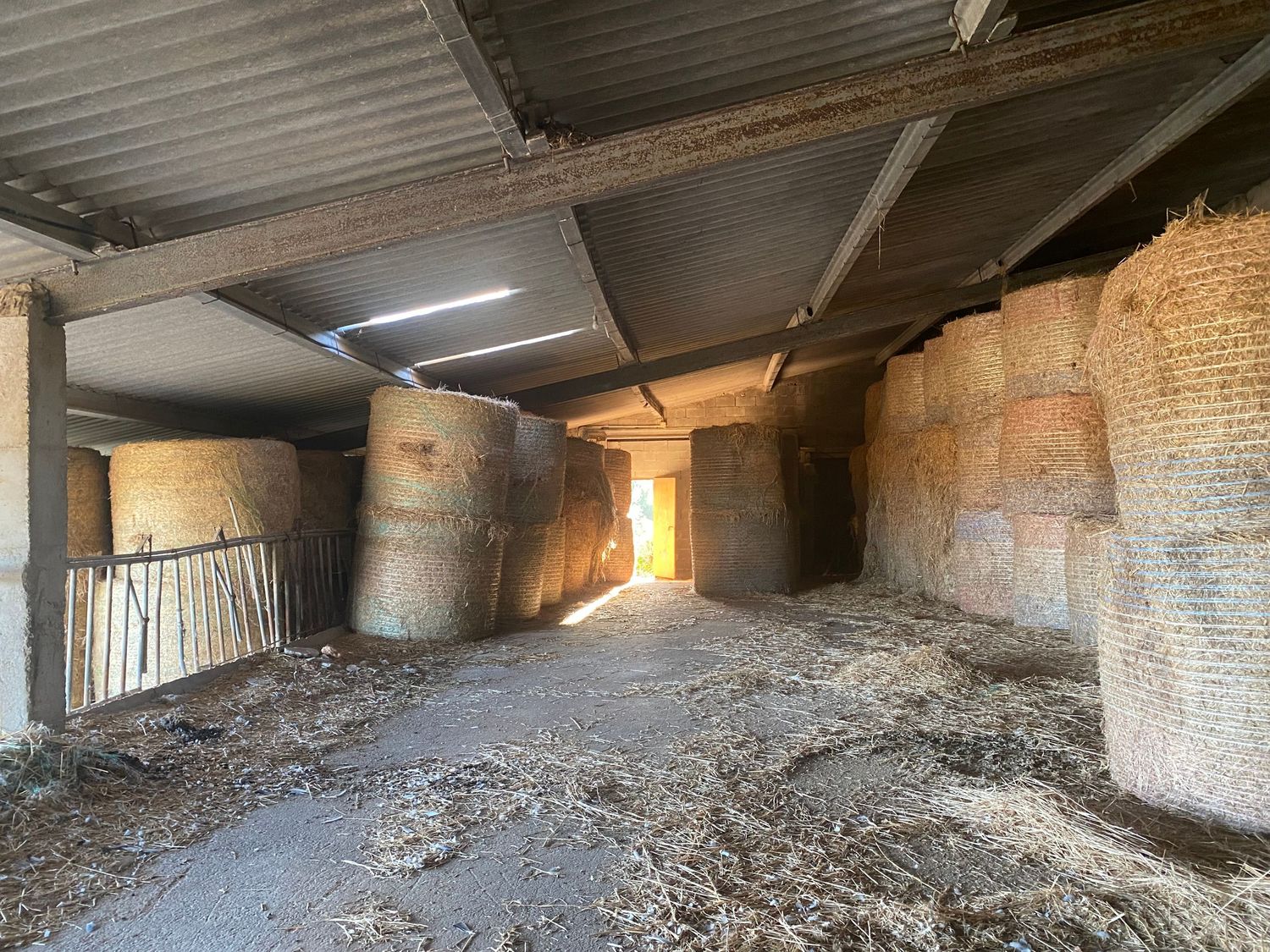 Interior of an old agricultural storage building with dirt floor and exposed brick walls.