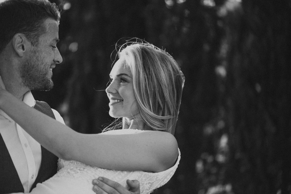 Black and white photo of a couple dancing and laughing together on their wedding day.