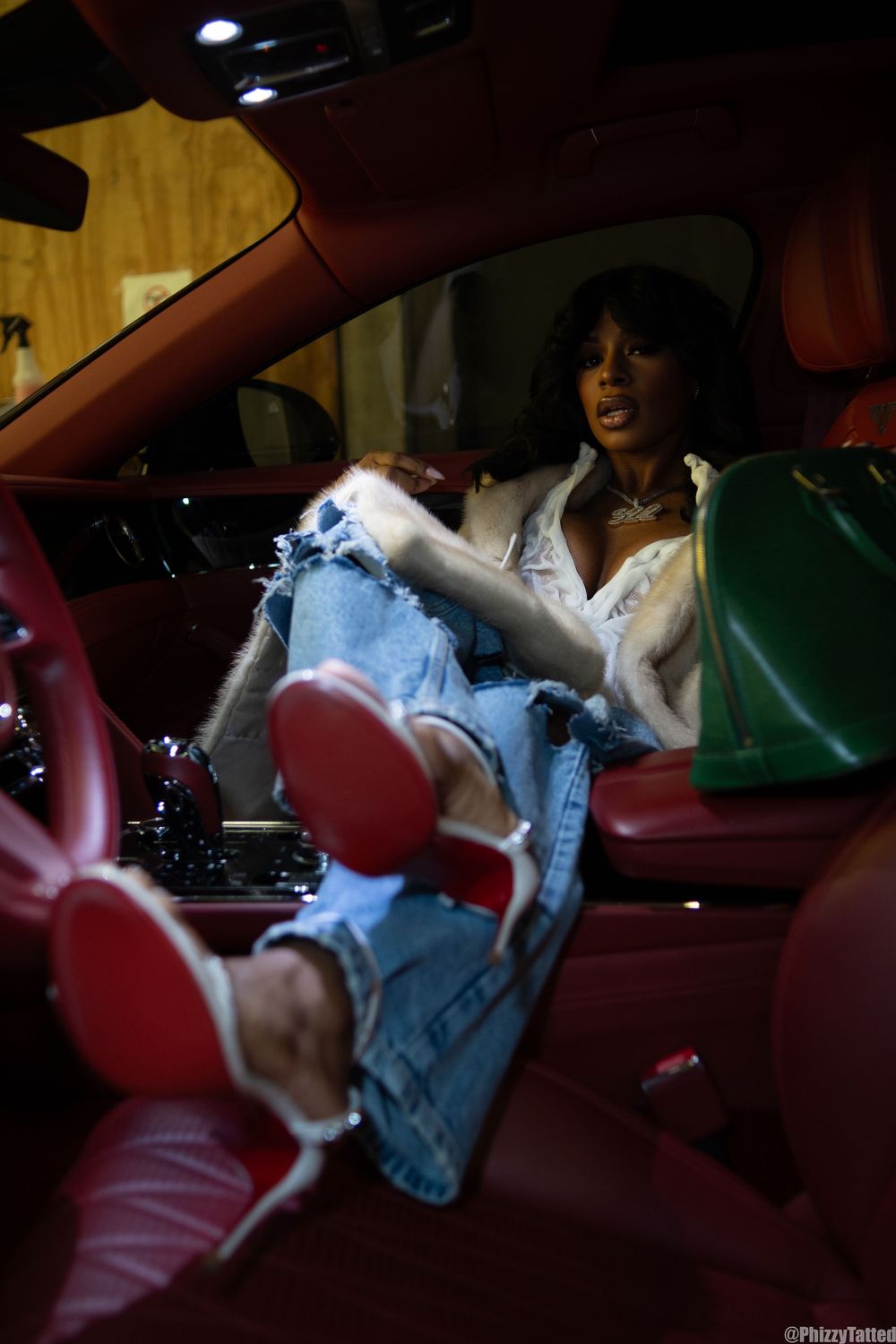 Figure in light denim and white top photographed inside car with red interior.