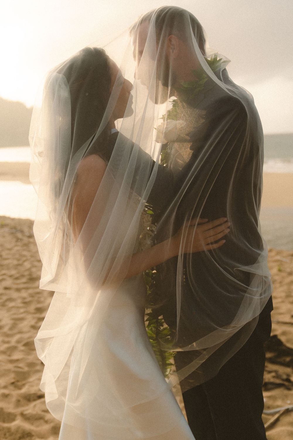 Wedding Couple under veil at sunset in Hanalei Bay