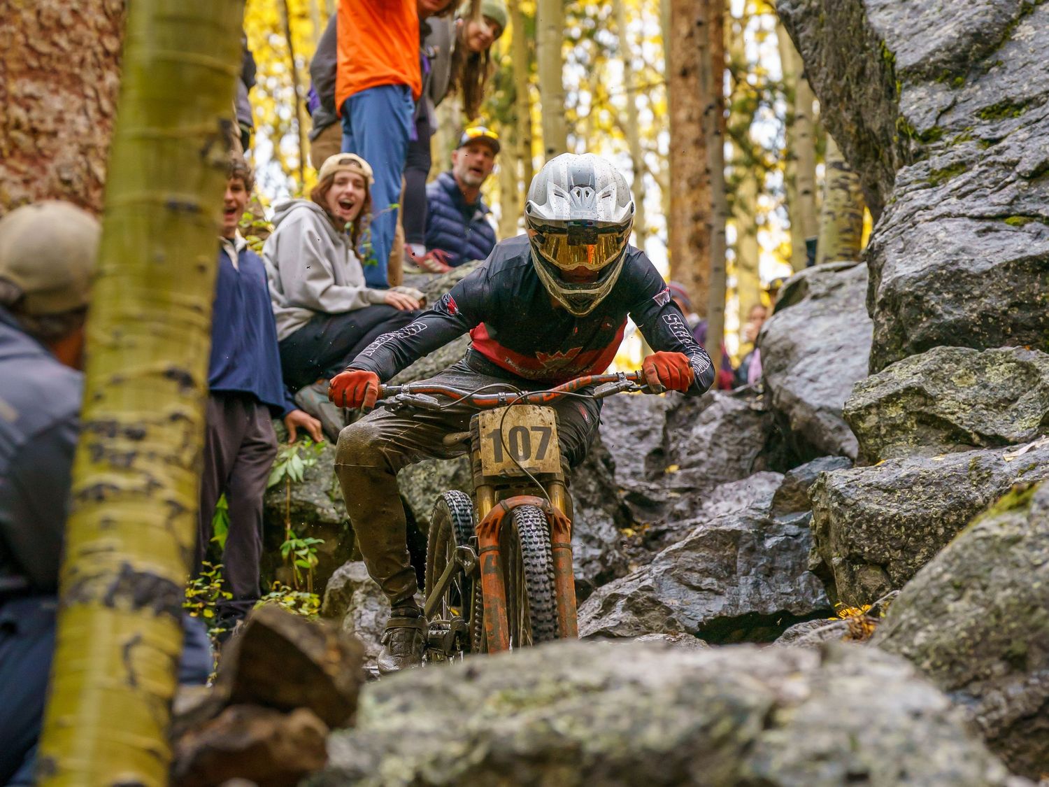 Mountain bikers racing through technical rock sections on a challenging forest trail.