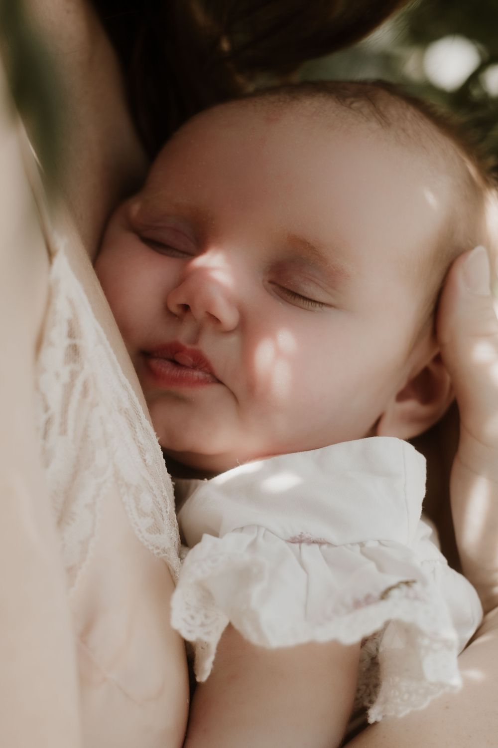 Peaceful closeup of sleeping baby in white ruffled collar with soft natural lighting.