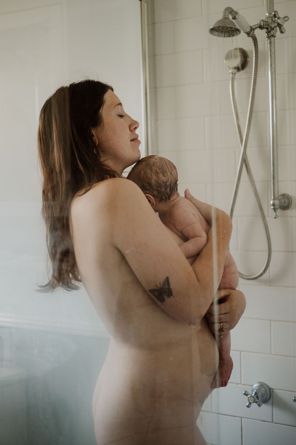 Tender moment captured in bathroom setting with soft natural window light.