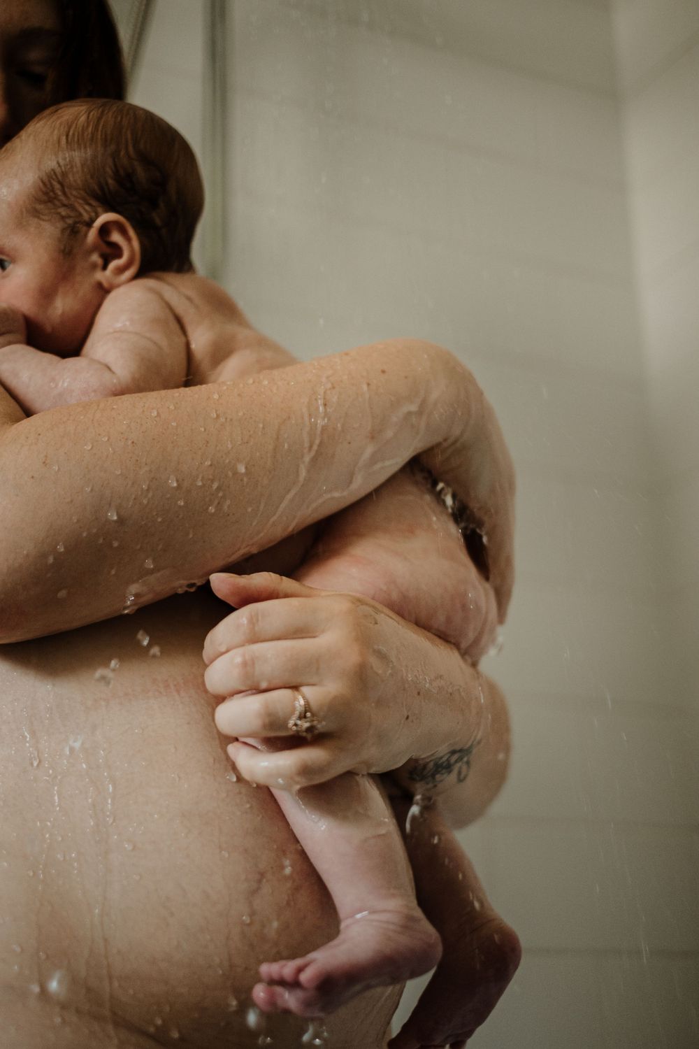 Intimate photograph capturing tender embrace with water droplets in bathroom setting.