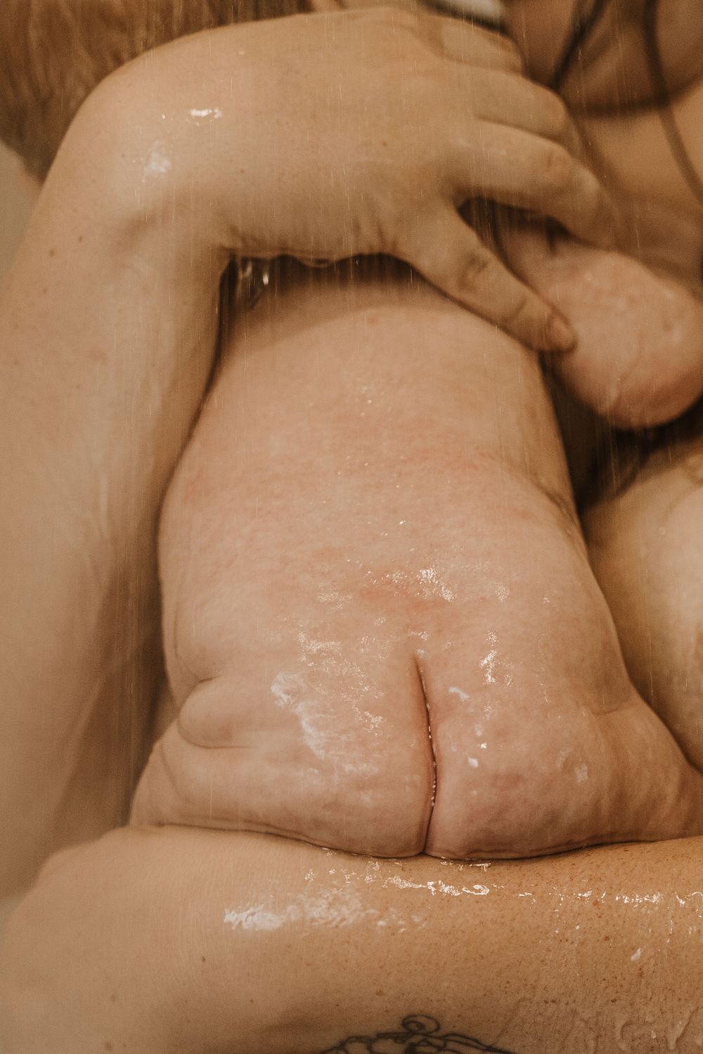 Close-up sepia-toned image showing a wet baby foot with wrinkled skin during bathtime.