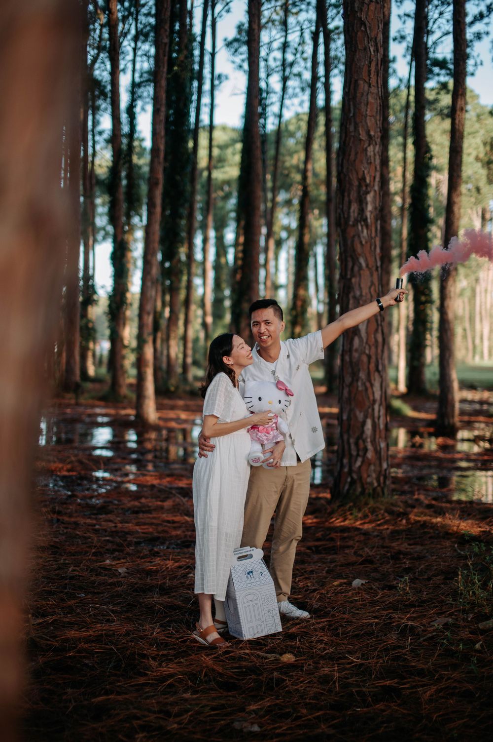 Couple with smoke effects and plush toy creating magical moments in a pine forest.