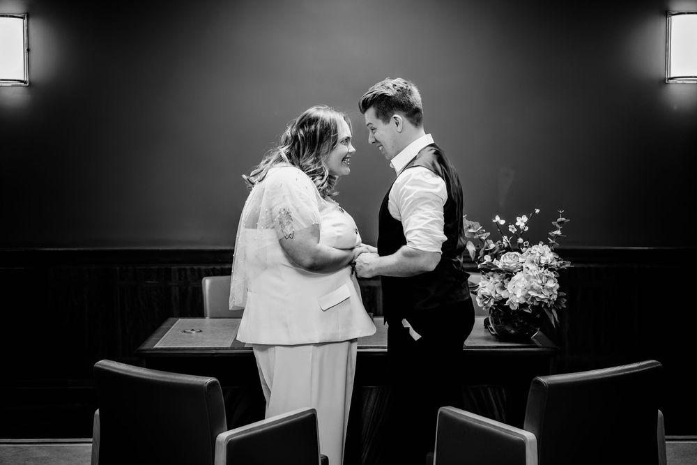 A tender moment between a couple in formal attire during an intimate indoor ceremony with floral arrangements.