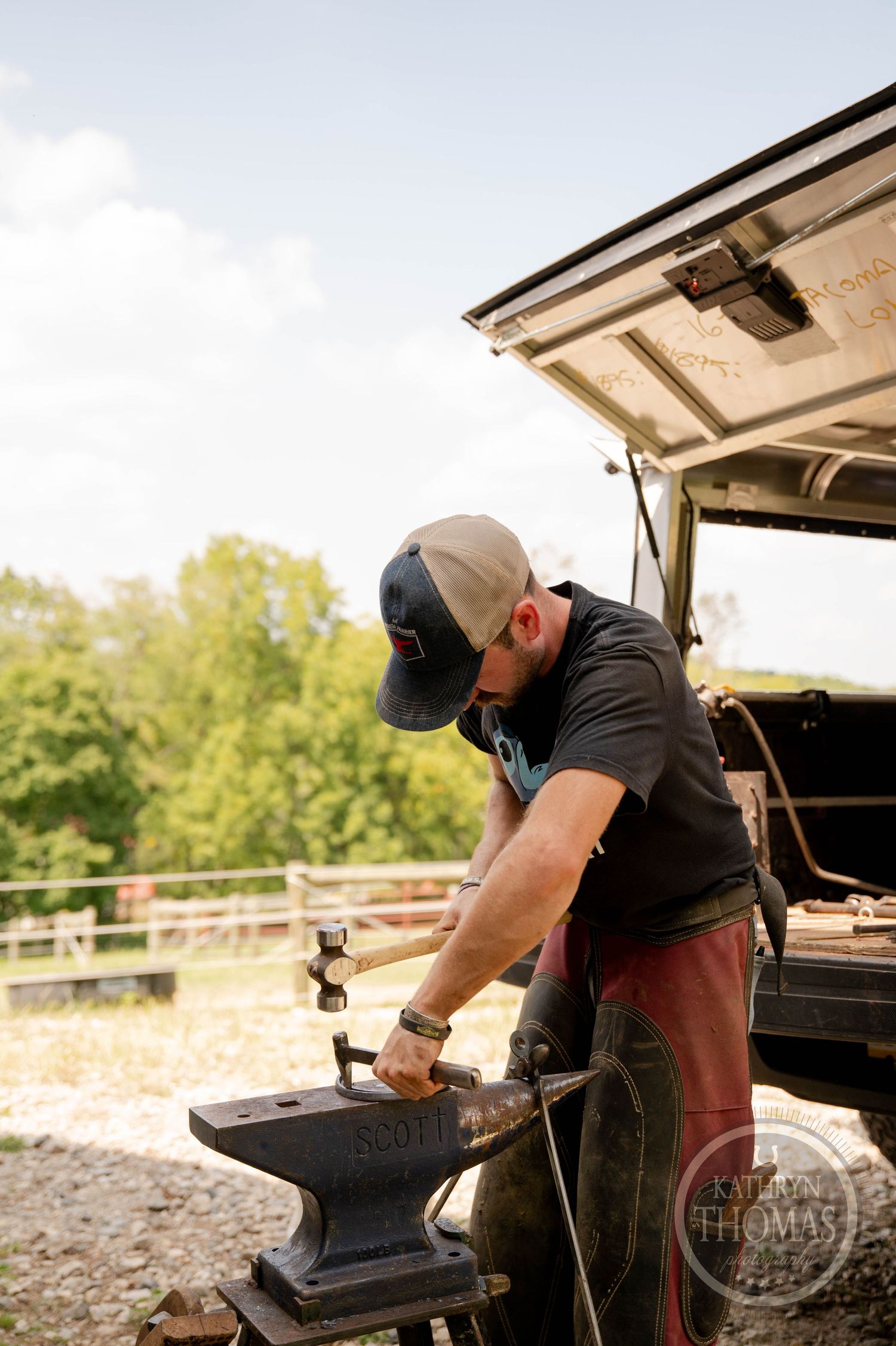 Outdoor farrier workshop setup showing metalworking on portable anvil stand.