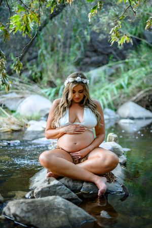 Expectant mother by a stream surrounded by nature in maternity photoshoot. Maternity photography in Las Vegas. Maternity photos in Las Vegas