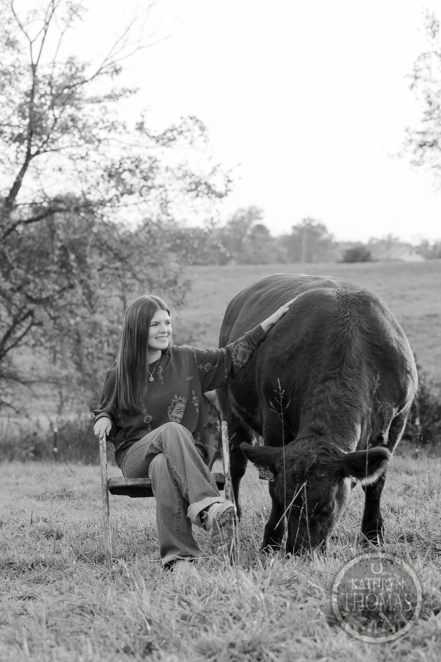 Black and white photograph showing a peaceful moment between someone in a chair and a grazing cow.