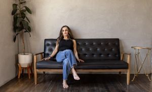 Lifestyle portrait of woman relaxing on leather mid-century modern sofa in minimal room setting.