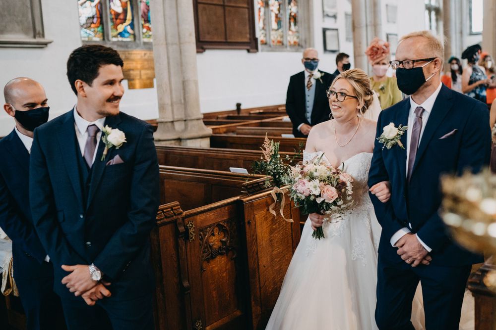 A traditional church wedding ceremony with attendees wearing protective face masks during the pandemic.