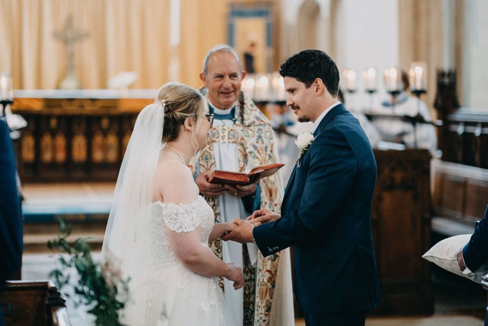 A couple exchanges vows during their wedding ceremony in a beautiful church with traditional decor.