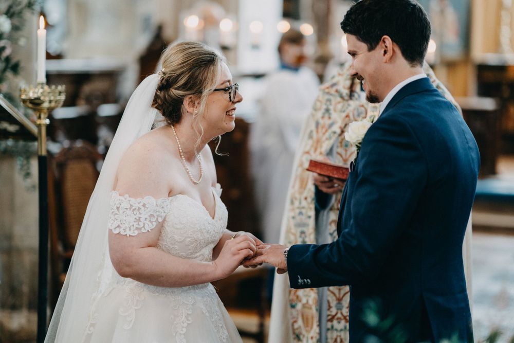 A couple exchanges vows during their church wedding ceremony with ornate decor and candlelight in the background.