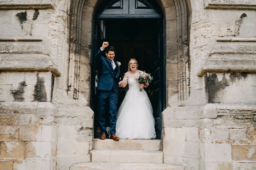 A bride and groom stand together in a historic stone church doorway during their wedding celebration in Stamford.