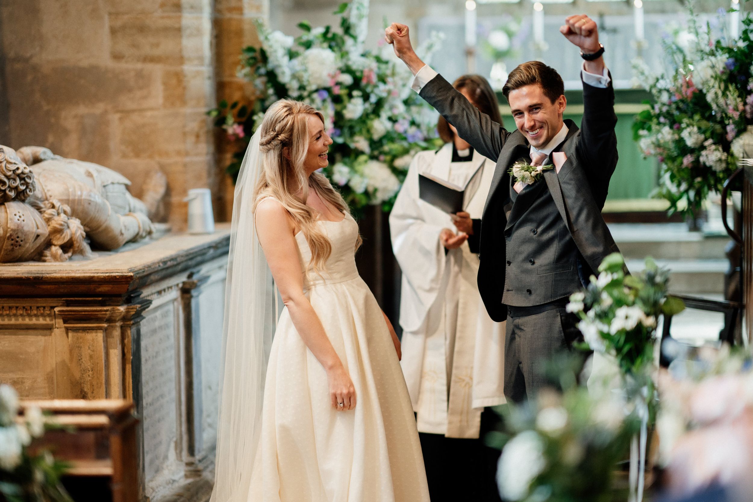 A joyful wedding celebration moment inside a stone church adorned with floral arrangements.