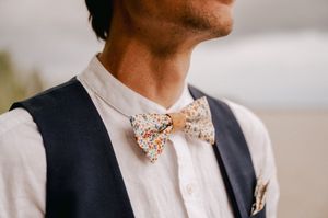 Person wearing a navy vest and floral bow tie adjusts their presentation at an elegant event.