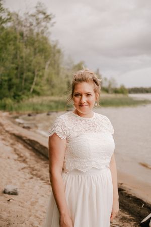 A candid sequence of a person in a white lace dress posing on a beach shoreline under cloudy skies.