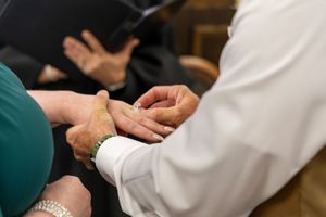 Close up of two people's hands during a medical consultation or examination in a healthcare setting.