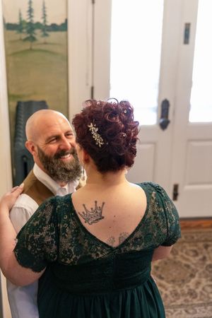 A couple at a wedding shows off a crown tattoo on the back of a green velvet dress.