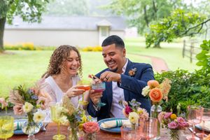 A romantic wedding reception scene with colorful floral arrangements and drinks on an outdoor table.