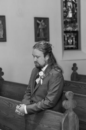 Black and white photo series showing a man in formal attire sitting thoughtfully at a wooden table in a church.