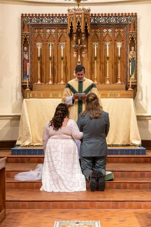 A wedding ceremony in progress at an altar with ornate wooden church decor.