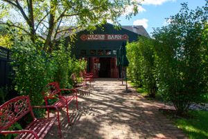 A garden entrance pathway with red benches and green foliage creating an inviting atmosphere.