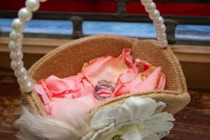 Wedding rings nestled in pink roses inside pearl-handled basket.