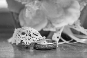 Black and white photo of wedding rings on delicate lace fabric.