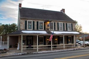 Historic stone two-story building with American flag at dusk.