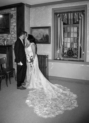 Black and white wedding photo showing couple with dramatic lace train in historic interior.