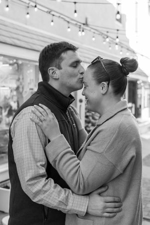 A couple shares an intimate moment in a shopping mall, shown in three sequential black and white photographs.