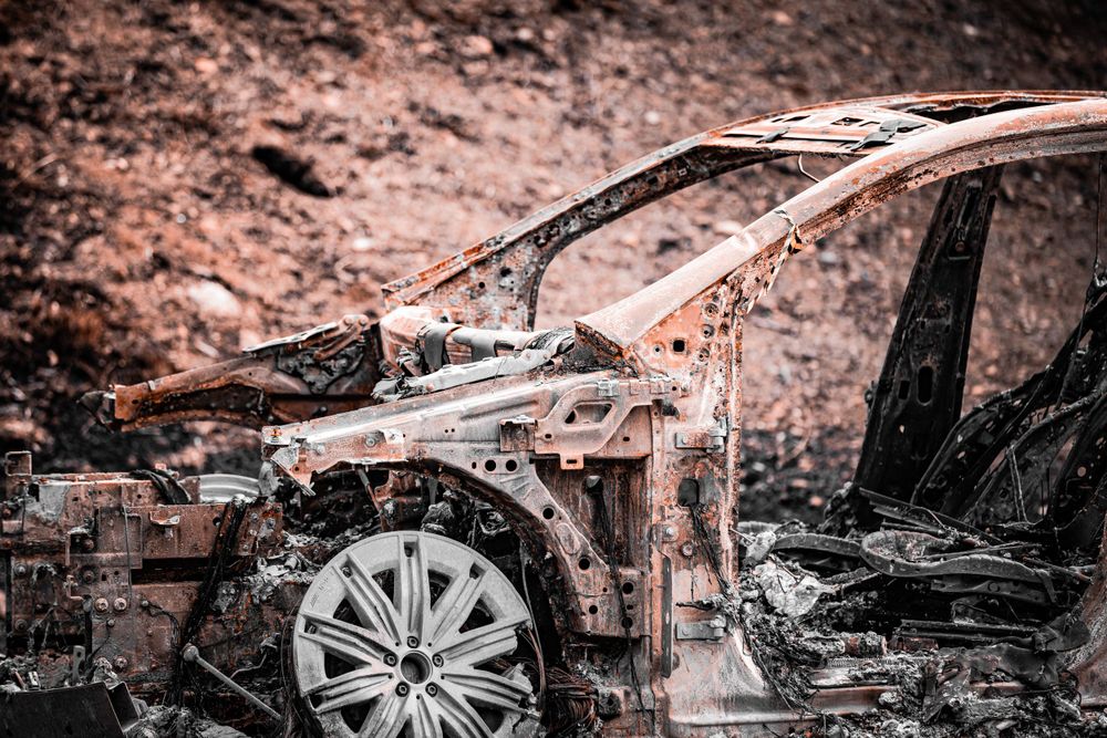 Burnt car wreckage showing melted and charred metal details.