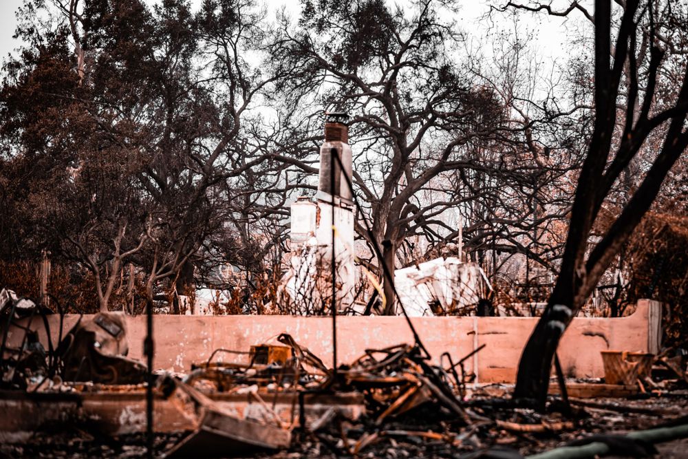American flag stands amid burned ruins and debris in warm toned lighting.