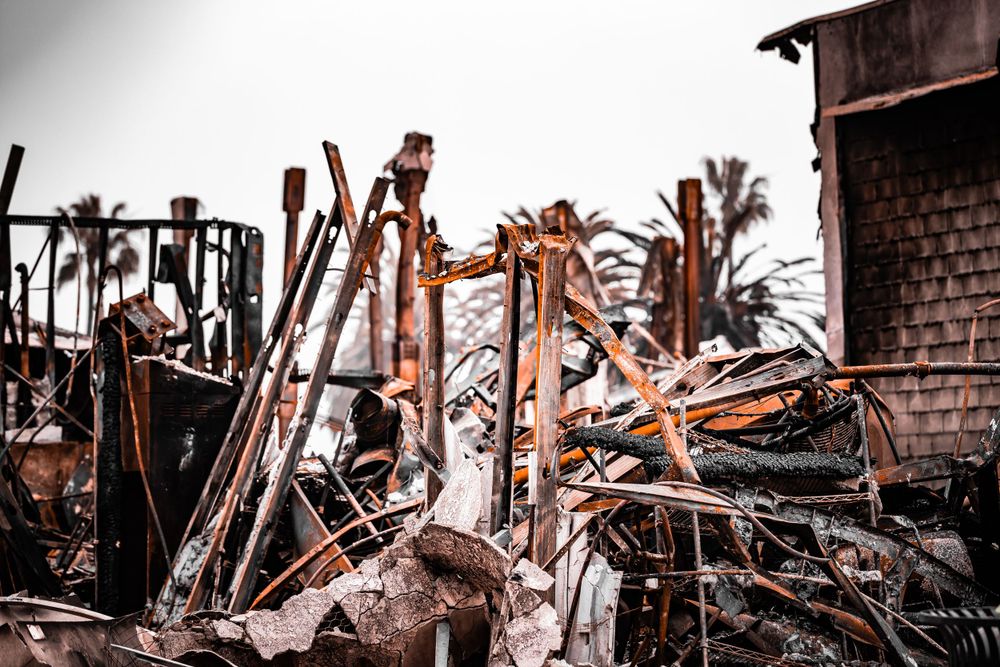 Burnt and charred wooden debris from destroyed structures showing aftermath of destruction.