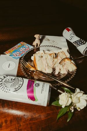 Wedding reception flat lay featuring sliced cake, scratch-off lottery tickets, Michelob Ultra, and White Claw on a decorative tray.