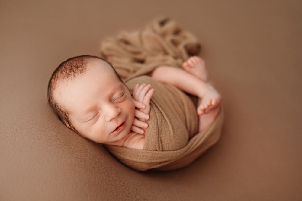 A collection of artistic newborn photography poses on a warm brown backdrop showing peaceful sleeping positions.
